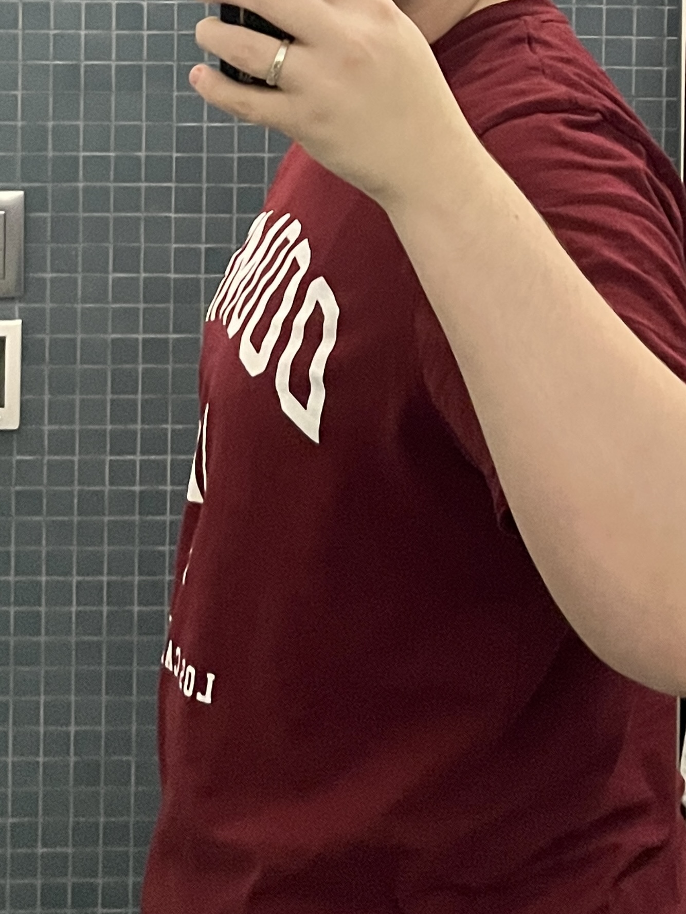 Trans man wearing a red shirt facing sideways